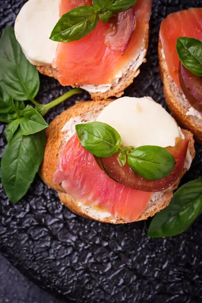 Crostini s lososem, mozarella, rajče a bazalka — Stock fotografie