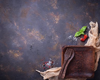 Boş ahşap tabak, çatal bıçak takımı, tuz, biber ve fesleğen