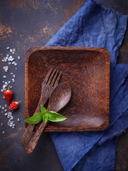 Boş ahşap tabak, çatal bıçak takımı, tuz, biber ve fesleğen