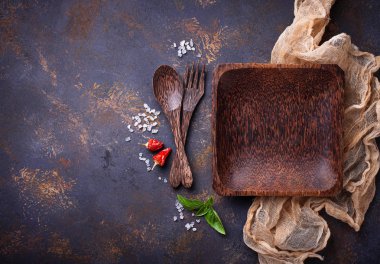 Boş ahşap tabak, çatal bıçak takımı, tuz, biber ve fesleğen