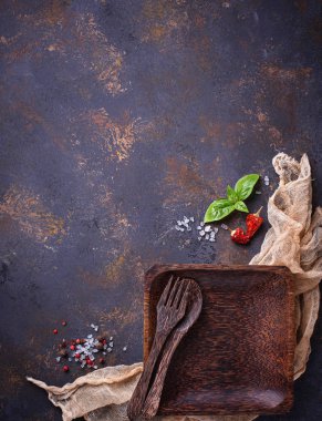 Boş ahşap tabak, çatal bıçak takımı, tuz, biber ve fesleğen