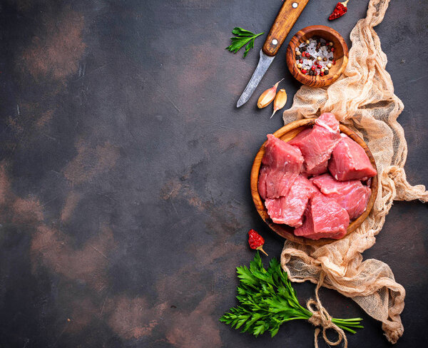 Raw chopped meat with spices on rusty background