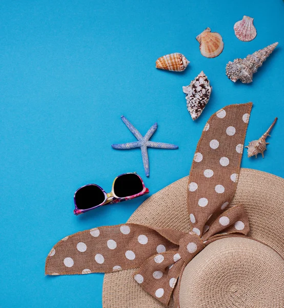 Соломенная шляпа и ракушки на синем фоне — стоковое фото