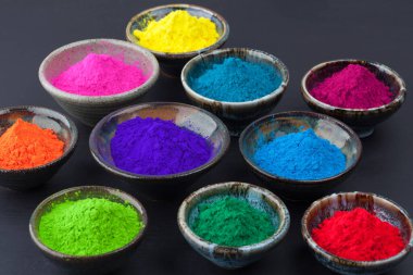 Pis siyah karatahta bardaklarda renkli Holi pudrası. Sığ alan derinliği.