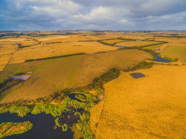 Avustralya kırsal manzarasının havadan görünüşü - gün batımında sarı çayırlar ve tepeler