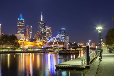 Melbourne CBD - APR 17 2016: Yarra nehri ve Flinders sokak istasyonu üzerinde Southbank yaya köprüsü ile gece manzarası.
