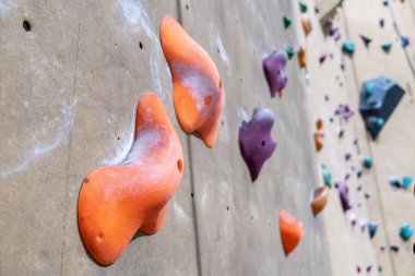 Large orange climbing holds with traces of chalk powder on blurred background clipart