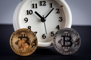 İki bitcoin ve antika çalar saat yakın plan.