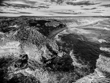Engebeli kıyı şeridinin hava manzarası, yüksek kontrastlı siyah beyaz biçimlendirilmiş.