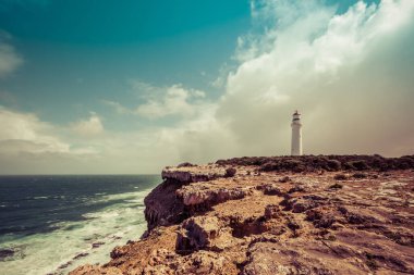 Cape Nelson deniz feneri fırtınalı gökyüzünün altında okyanusun üzerindeki engebeli bir uçurumda duruyor. Victoria, Avustralya. Görüntü geriye dönük gibi.
