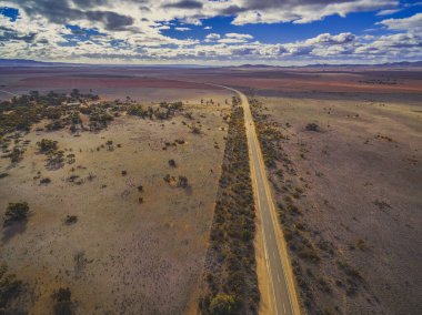 Güney Avustralya 'nın geniş ovalarından geçen kırsal yol güzel bulutların altında - hava manzarası