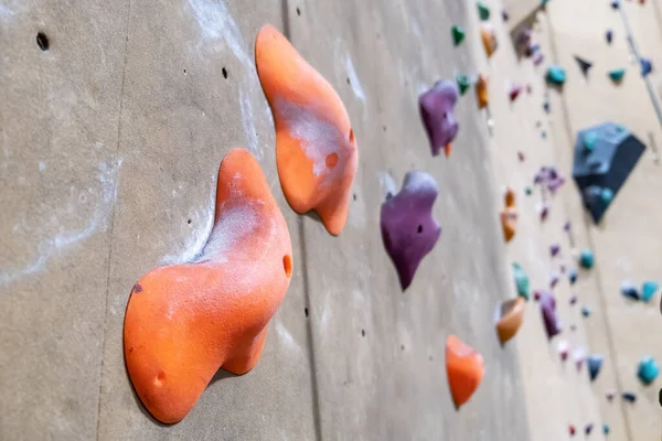 Large orange climbing holds with traces of chalk powder on blurred background