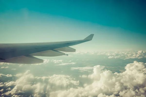 青い空の下で白いふわふわの雲の上を飛んでいる商業飛行機の翼のコピースペース — ストック写真