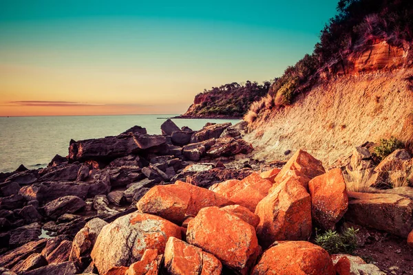 手前にオレンジの岩が見える夕日の海 — ストック写真
