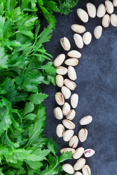 Curly-leaf and flat leaf parsley with pistachios on grunge background with copy space. Top view.