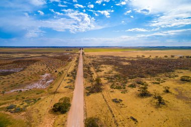 Avustralya kırsalından dümdüz giden mühürsüz bir yol - hava manzaralı