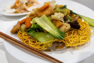 Kızarmış sebzeli çıtır yumurtalı erişte. Yanında yemek çubuğu olan vejetaryen Vietnam yemeği.