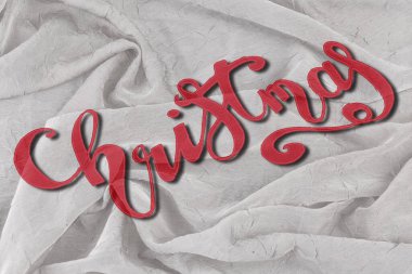 Noel - kumaş katlama arka planında kırmızı renkli zarif fırça harfi
