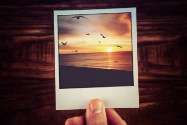 Okyanus kıyısında kuş siluetleri ve bulutlarla dolu güzel günbatımının anlık fotoğraf kartpostalı. Kopya alanı ile hatıra defteri şablonunu seyahat et