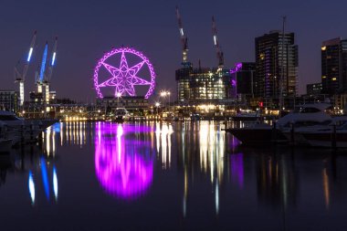 Melbourne, Avustralya - 21 Şubat 2016: Docklands, Melbourne 'da mor renkle aydınlatılmış gözlem tekeri Yarra Nehri' ni yansıtıyor. Gece sahnesi.