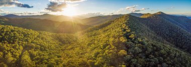 Aerial panorama of beautiful Australian Alps at sunset. Forested hills and rural road clipart