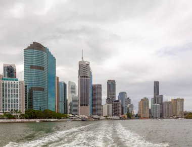 Brisbane Nehri 'ne yelken açmak gökdelenlerden uzaklaşmak geride su izi bırakmak