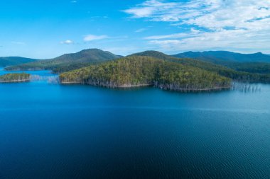 Queensland, Avustralya 'daki Advancetown Gölü' ndeki su ve orman tepelerinden büyüyen çıplak ağaçların hava manzarası.