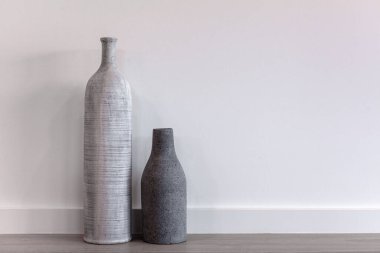 İki dekoratif modern vazo - uzun ve kısa tahta zemin üzerinde beyaz duvara karşı fotokopi alanı ile