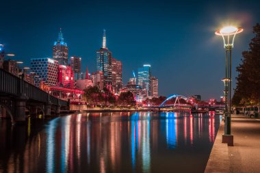 Melbourne CBD - APR 17 2016: Yarra nehri ve Flinders sokak istasyonu üzerinde Southbank yaya köprüsü ile gece manzarası.