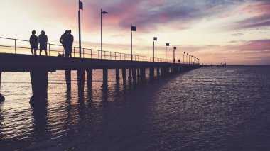 Gün batımında Frankston İskelesinde yürüyen siluetler.