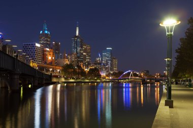 Melbourne CBD - APR 17 2016: Yarra nehri ve Flinders sokak istasyonu üzerinde Southbank yaya köprüsü ile gece manzarası.