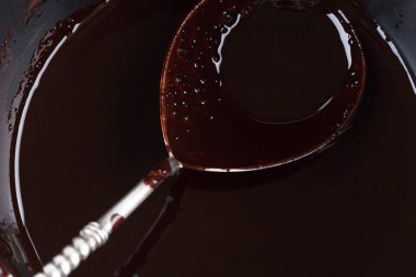 Bir tavada erimiş çikolatayla doldurulmuş klasik gümüş kaşığın aşırı yakın çekimi.