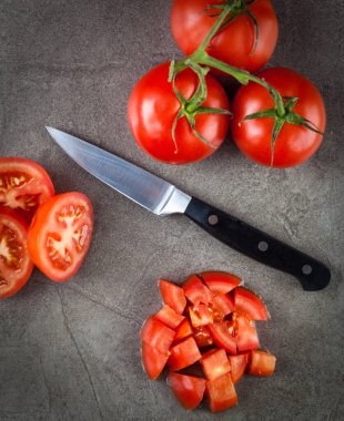 Domatesler ve mutfak bıçağı desenli taş yüzeyde sıralanmış. Üst görünüm.