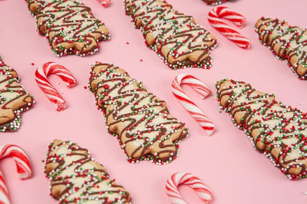 Christmas desserts - trees biscuits with candy canes on pink background with shallow focus