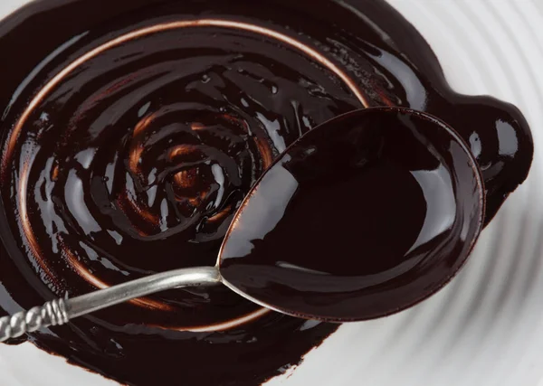 プレート上に溶かしたダークチョコレートで覆われた大きなスプーンの閉鎖 — ストック写真