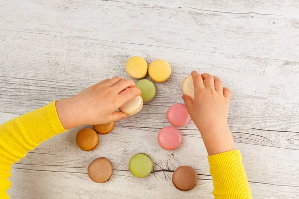 Girl Hands Yellow Sleeves Playing Macarons Wooden Table Top View — Stock Photo, Image