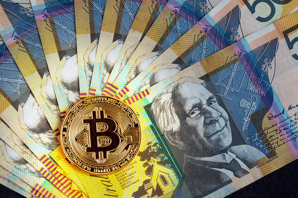 Golden Bitcoin glowing on top of Australian 50 dollar banknotes closeup