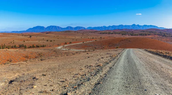 Kel turuncu tepelerden geçip Güney Avustralya 'daki Ikara-Flinders Ulusal Parkı' ndaki dağlara uzanan çakıl yolu.