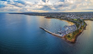 Mornington İskelesi ve Peninsula sahil şeridinin hava panoramik manzarası yat kulübü, demirli tekneler ve gün batımında banliyö bölgesini gösteriyor. Melbourne, Victoria, Avustralya