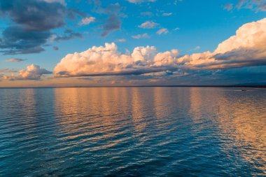 Okyanus kıyısında gün batımı - sakin körfez sularının üzerindeki bulutlar