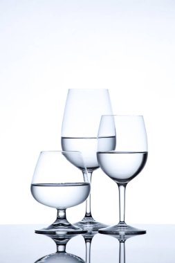 Beyaz arka planda su dolu cam eşyalar ve şişe.