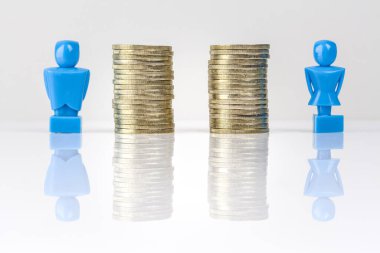Erkek ve dişi heykelcikler eşit madeni paraların yanında duruyor. Gelir eşitliği kavramı.