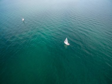 Hava görüntüsü, turkuaz sularda yüzen iki yelkenliye bakıyor.