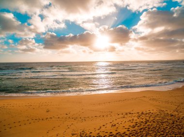 Okyanusun üzerinde parlayan altın günbatımının havadan manzarası