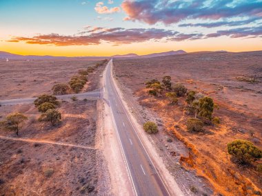 Gün batımında çölden tepelere giden kırsal yol. Hava manzaralı.