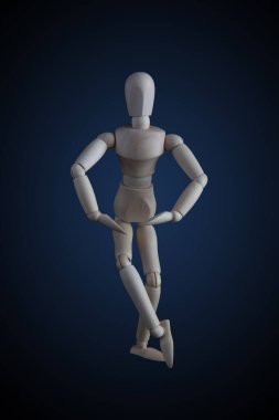 Ahşap heykel bacak bacak üstüne atmış zarif dans ederken koyu arkaplanda hareket ediyor.