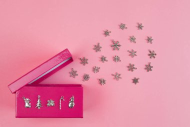 Kar taneleri pembe arka plandaki hediye kutusundan fırlıyor. Noel teması