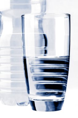 Su şişesinin önündeki su bardağı beyaza izole edilmiş.