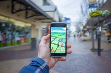Melbourne, Avustralya - 12 Ağustos 2016: Halka açık bir yerde Pokemon Go oyunu ile iPhone 6 'yı tutan erkek