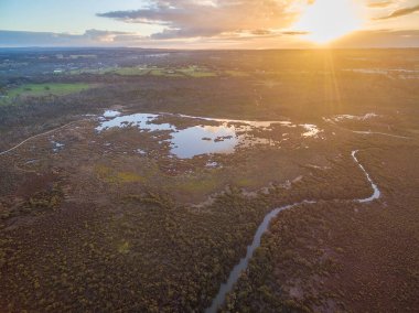 Mangrov ve nehrin üzerinde ufkun üzerinde batan güneşin havadan görünüşü. Melbourne, Avustralya